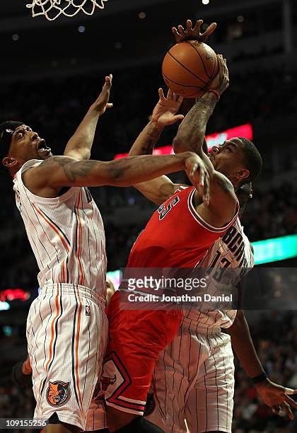 Derrick Rose of the Chicago Bulls tries to shoot under pressure from Dominic McGuire and Nazr Mohammed of the Charlotte Bobcats at the United Center...