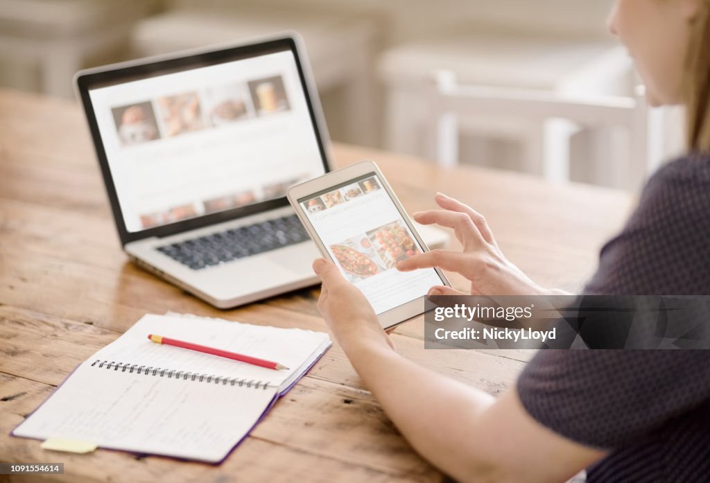 Frau, betrachten ihre Website auf Tablet und Notebook