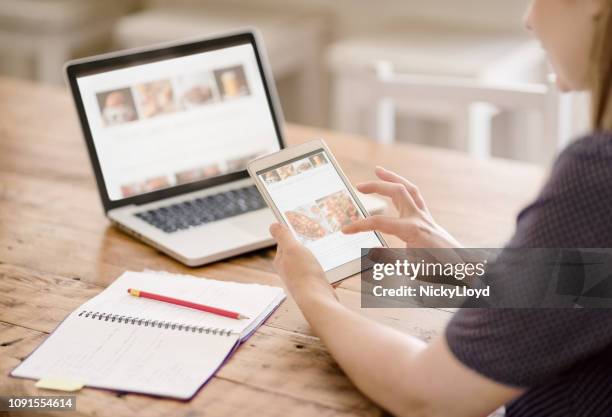 woman viewing her website on a tablet and laptop - author laptop stock pictures, royalty-free photos & images