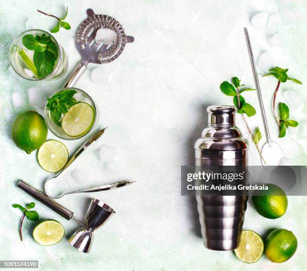 summer drink mojito ingredients - white rum, lime, mint, and ice, and set of bar tools for making a cocktails arranged on a stone background. - cocktail shaker stock pictures, royalty-free photos & images