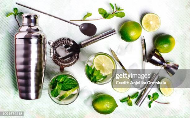 summer drink mojito ingredients - white rum, lime, mint, and ice, and set of bar tools for making a cocktails arranged on a stone background. - drinks utensil stock pictures, royalty-free photos & images