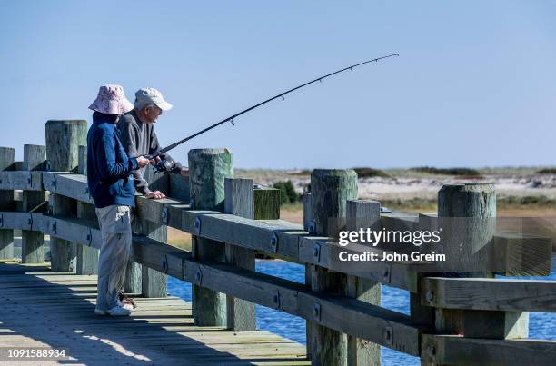 Mature couple fishing from bridge, Chappaquiddick.