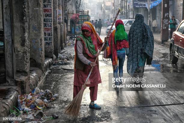 In this picture taken on January 8 a street sweeper cleans a road during a morning of heavy air pollution at Chandni Chowk market in New Delhi. -...