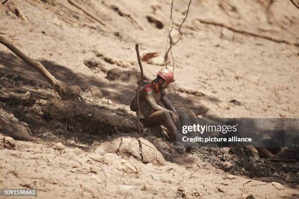 Dpatop - 30 January 2019, Brazil, Brumadinho: A firefighter sits full of mud and cries at the edge of the rescue work after the dam burst at an iron...