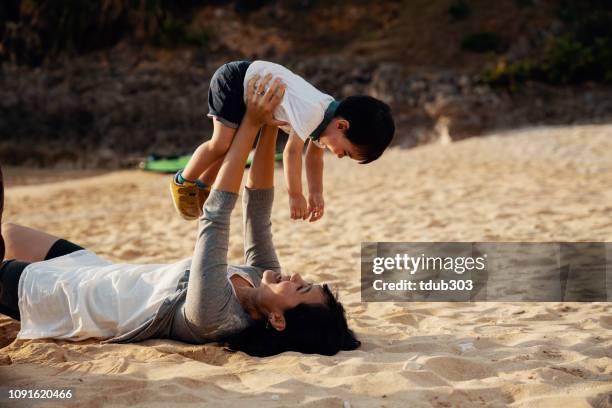 mother and young son playing together on a beach while on vacation - summer memories stock pictures, royalty-free photos & images