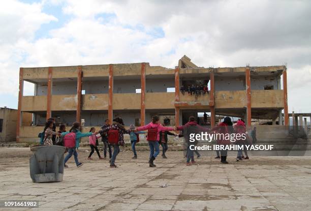 Syrian children dance together in a circle in the courtyard of a school which was hit by bombardment in the district of Jisr al-Shughur, in the west...