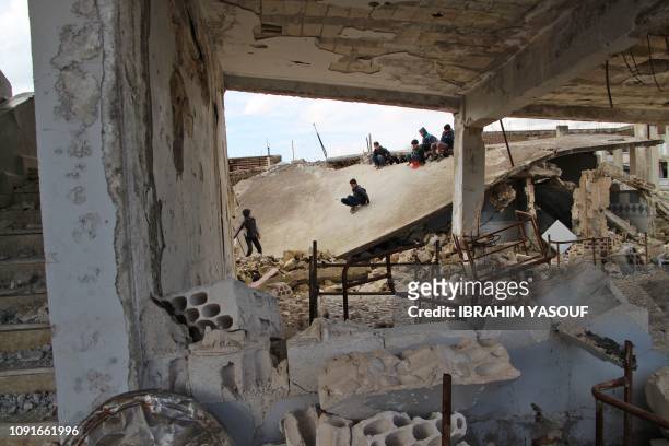 Syrian children slide on the collapsed roof of a school which was hit by bombardment in the district of Jisr al-Shughur, in the west of the mostly...