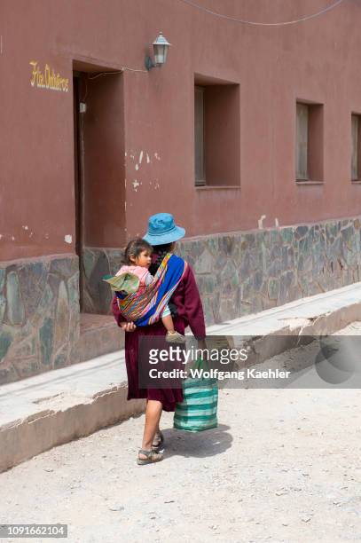 Street scene with native woman carrying a child in a back sling in the small village of Purmamarca, Jujuy Province, Argentina.