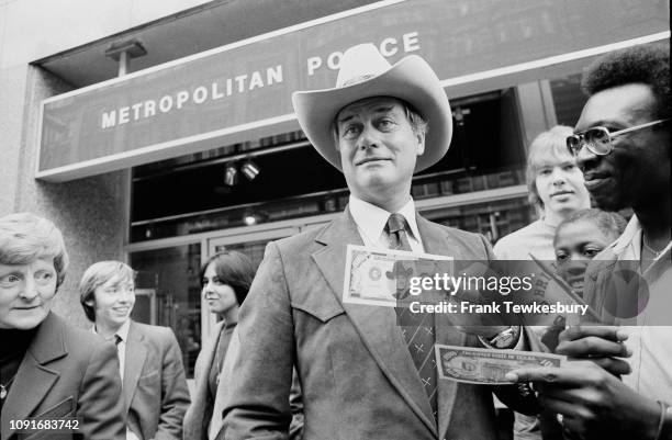 American actor, director and producer Larry Hagman signing $100 bill from television show Dallas, in which he plays 'JR Ewing', outside the...