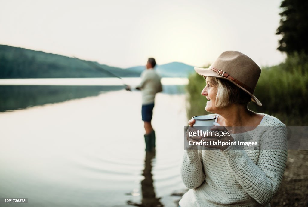 A senior couple fishing on a lake at sunset.