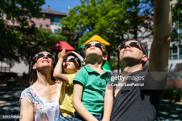 toute la famille regarder une éclipse solaire dans les rues de la ville dans un parc public - éclipse solaire photos et images de collection