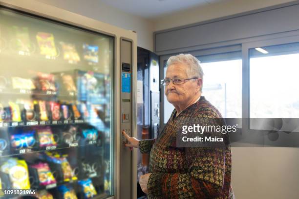 senior woman using a vending machine - vending machine stock pictures, royalty-free photos & images