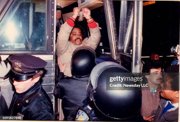 The Rev. Al Sharpton raises his handcuffed hands as he boards a police bus after he was arrested at LaGuardia Airport in Queens, New York on January...