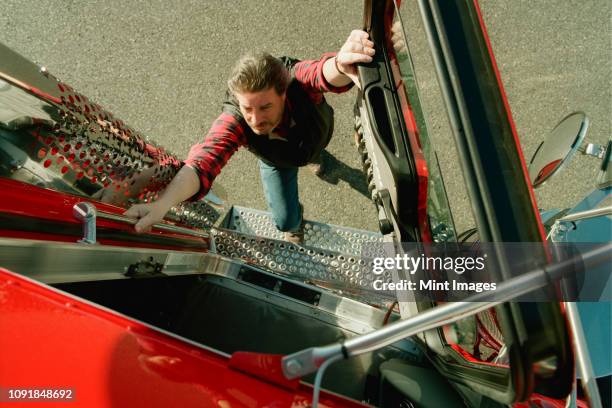 a view looking down of a truck driver climbing into the cab of a commercial truck . - truck driver occupation stock pictures, royalty-free photos & images