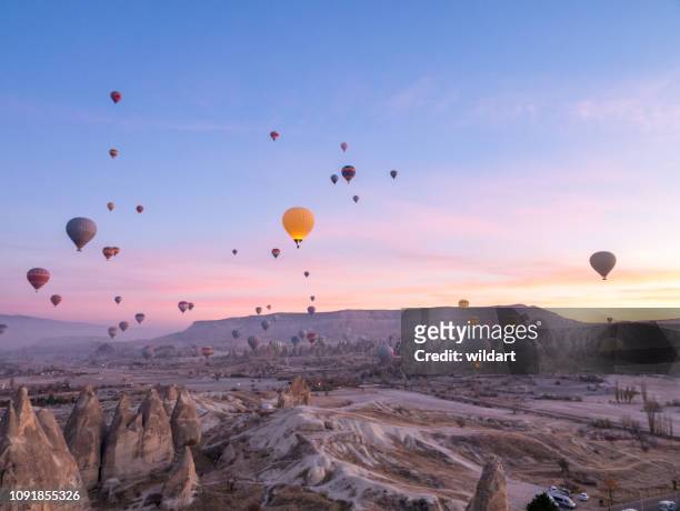 hot air balloons flying in red and rose valley in goreme in cappadocia in turkey - cappadocia hot air balloon stock pictures, royalty-free photos & images