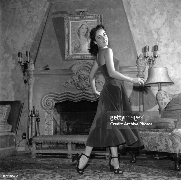 British-born actress Elizabeth Taylor wearing a velvet evening dress and high-heeled shoes, circa 1950.