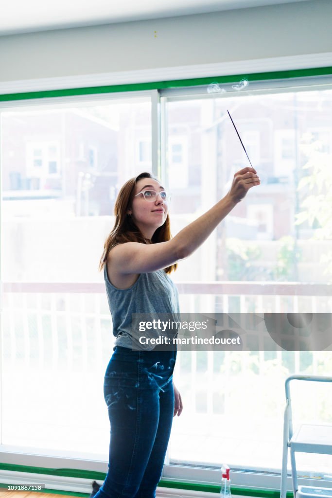 Millennial young woman purifying new apartment with incense.