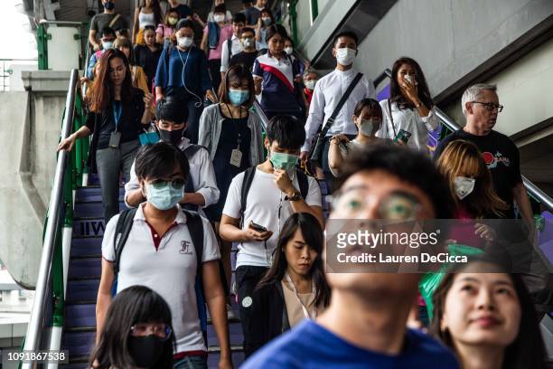 People wearing masks exit the BTS train station at the Asoke intersection on January 31, 2019 in Bangkok, Thailand. The Thai Government has ordered...