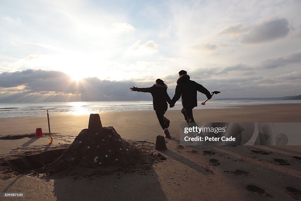 Young couple playing on beach in winter