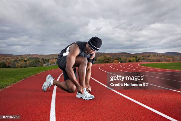 man tying shoes on track - kneeling stock pictures, royalty-free photos & images