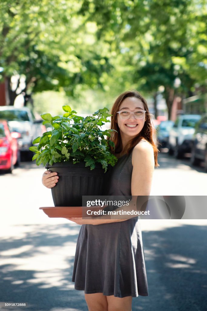 Millennial young woman moving a plant in new apartment.