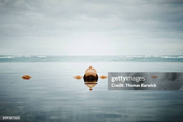 woman floating on back in infinity pool - infinity pool stock pictures, royalty-free photos & images