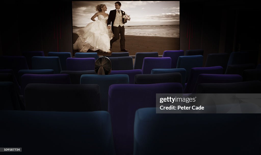 Woman sat alone in cinema watching romantic film