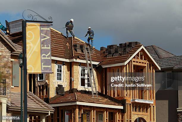 Construction workers move roofing tiles onto the roof of a newly built home in a housing development February 16, 2011 in Dublin, California. New...