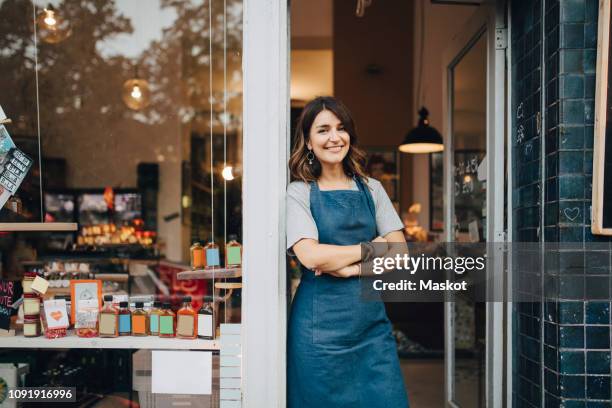 portrait of confident female owner standing at entrance of deli - pequeña empresa fotografías e imágenes de stock