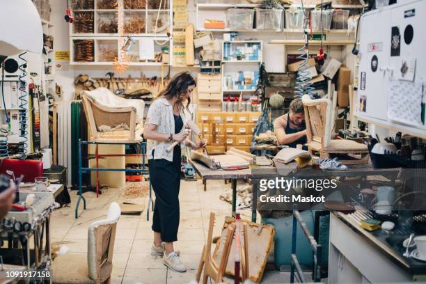 male and female upholstery workers working in workshop - stoffeerder stockfoto's en -beelden