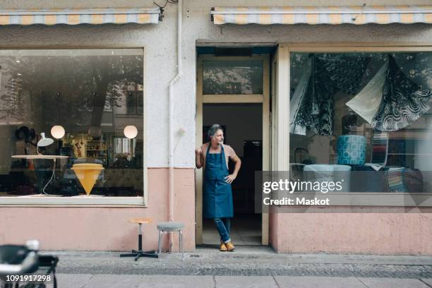 full length of male upholstery worker looking away while standing at workshop entrance - escaparate fotografías e imágenes de stock