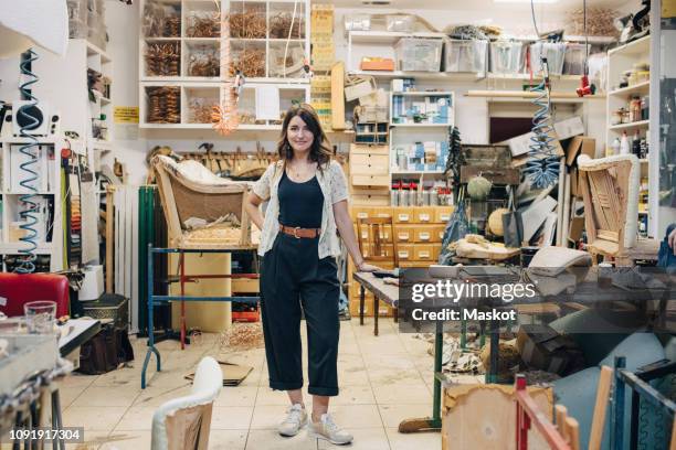 portrait of confident female upholstery worker standing in workshop - stoffeerder stockfoto's en -beelden