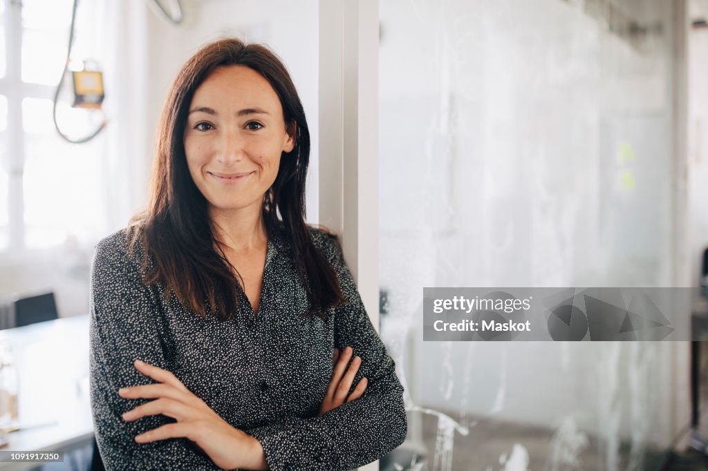 Confident creative businesswoman standing with arms crossed in office