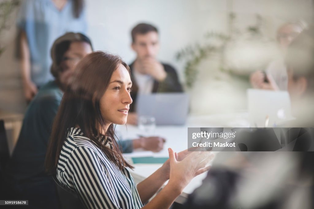 Businesswoman explaining colleagues during brainstorming session in creative office