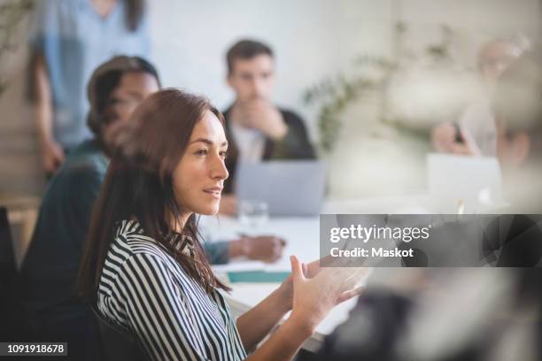 businesswoman explaining colleagues during brainstorming session in creative office - explicar fotografías e imágenes de stock