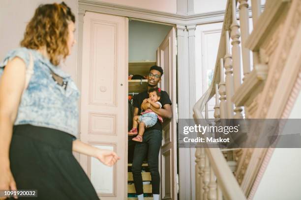 young man looking at woman while carrying daughter at doorway - apartment exterior ストックフォトと画像