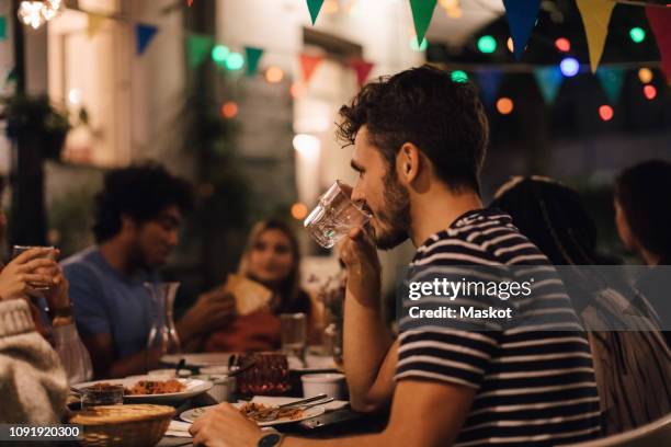 young man drinking water while having dinner with friends during garden party - focus on foreground food stock pictures, royalty-free photos & images