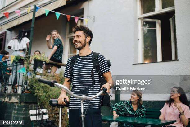 smiling young man standing with bicycle in backyard - public transport stock-fotos und bilder