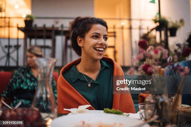 smiling young woman looking away while sitting at table during dinner party - inviter photos et images de collection