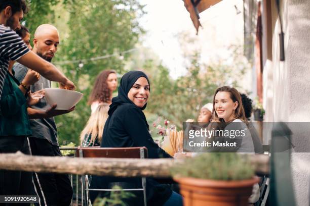 portrait of young woman sitting with friends in balcony during party - religion stock-fotos und bilder