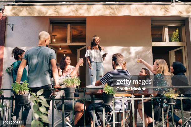 multi-ethnic friends enjoying at balcony during party - standing table outside stock pictures, royalty-free photos & images