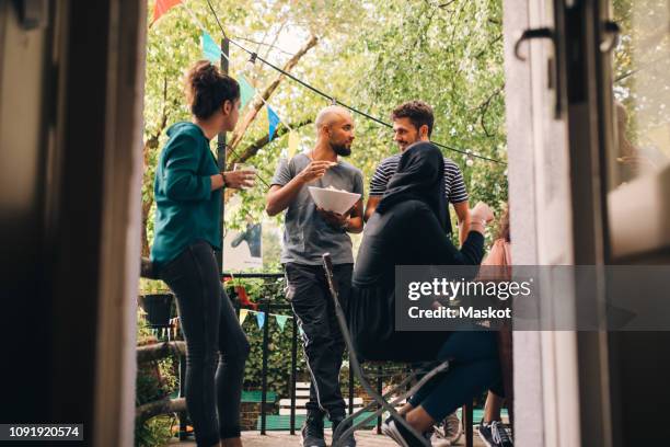 multi-ethnic male and female friends at balcony seen through doorway - balcony decoration stock pictures, royalty-free photos & images