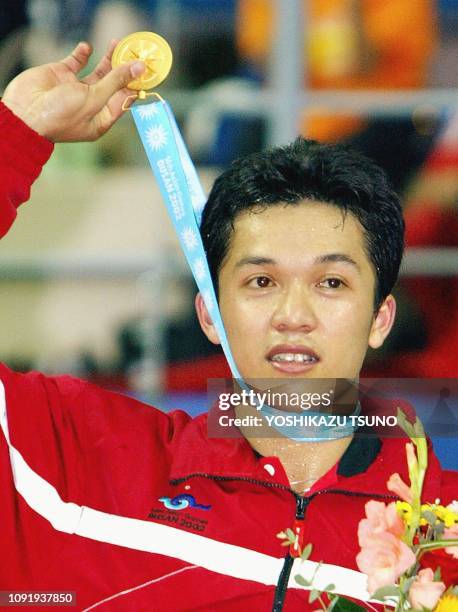 Indonesia's Taufik Hidayat raises his gold medal to show Indonesian supporters after his win over South Korea's Lee Hyun-Il in the men's badminton...