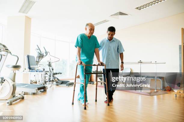 senior man walking frame met fysiotherapie sportschool - looprek stockfoto's en -beelden