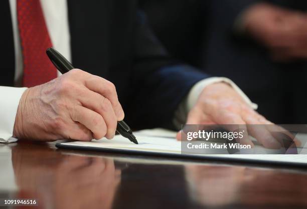 President Donald Trump holds up an executive order he signed during a meeting with members of Congress and American manufacturers, to strengthen the...