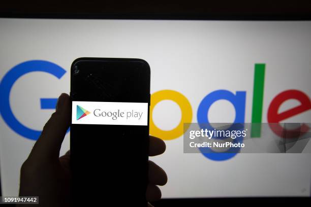 The logo of Google Play is seen on a screen. In the background there is the logo of Google. Alphabet is the mother company of Google. It has a...