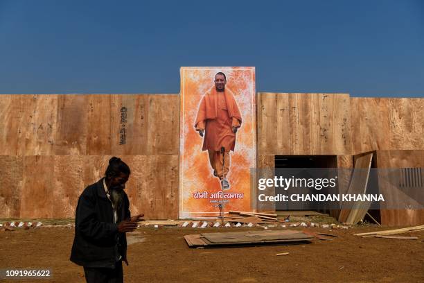 In this photograph taken on January 16 an Indian man walks past a poster of Chief Minister of Uttar Pradesh Yogi Adityanath displayed at a government...