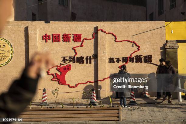 Tourism slogan and a map of Xinjiang are displayed on a wall in front of a residential compound in Kashgar, Xinjiang autonomous region, China, on...