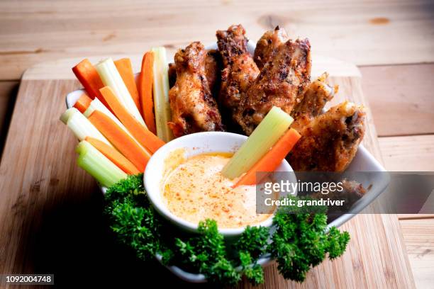 een kom gezond gebakken gegrilde kippenvleugeltjes vergezeld van hete saus selderij en worteltjes - dip stockfoto's en -beelden
