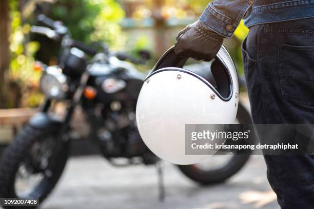 biker riding wear jeans with helmet and classic motorcycle blur background - women black and white motorcycle fotografías e imágenes de stock